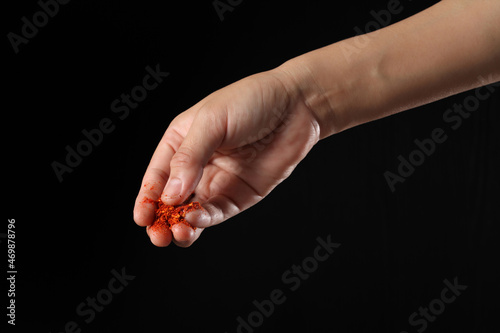 Hand holding cayenne pepper on black background