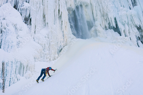 Female ice climber ascending snowy hill
