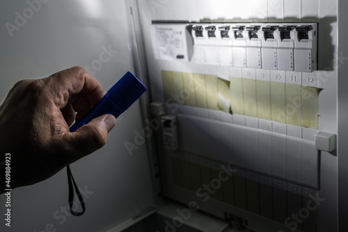 Sicherungskasten mit Sicherungen in einem Verteilerkasten während eines Stromausfall mit  blauer Taschenlampe beleuchtet die ein Mann in der Hand hält, Deutschland