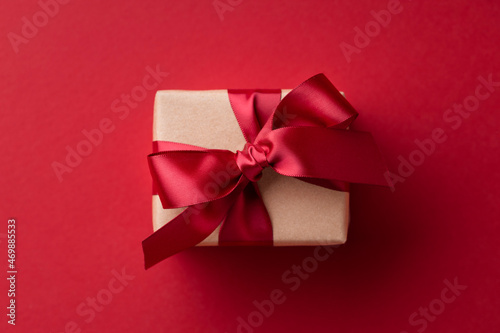 Close up of gift box tied red ribbon on red background.