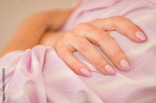 hands with pink manicure on nails after care in the salon