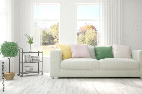 Stylish room in white color with sofa and autumn landscape in window. Scandinavian interior design. 3D illustration