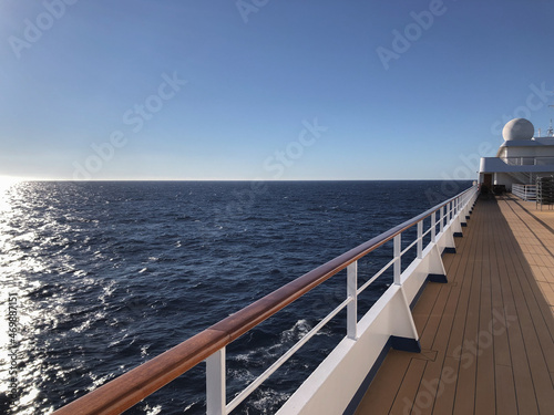 White luxury cruiseship cruise ship liner Silver Shadow on blue sea with panoramic seascape ocean views from deck on sunny blue sky day twilight blue hour with parts of deck and railing photo