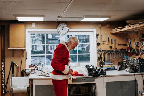 Senior man putting Santa costume on photo