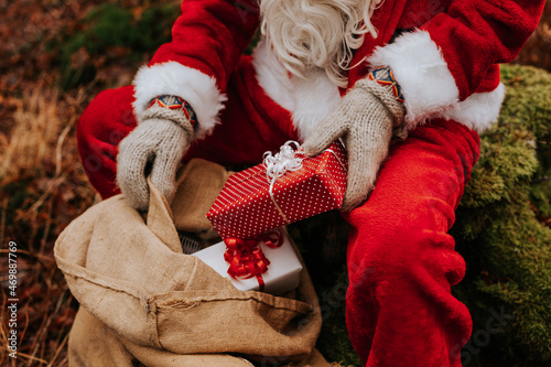 Person wearing Santa costume holding Christmas present photo