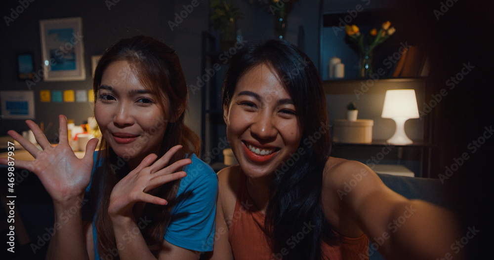 Teenager Asia  women feel happy smiling selfie and look at camera with relax in living room at home night. Cheerful Roommate ladies video call with friend and family, Lifestyle woman at home concept.