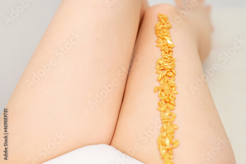 Sugaring concept. Wax granules lying in a row on female legs close up