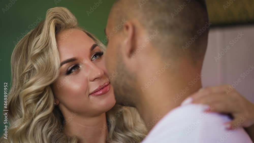 Cheerful loving woman with curly hair embraces husband standing together in spacious hotel room at honeymoon close view slow motion Cheerful loving woman with curly hair embraces husband standing together in spacious hotel room at honeymoon close view slow motion