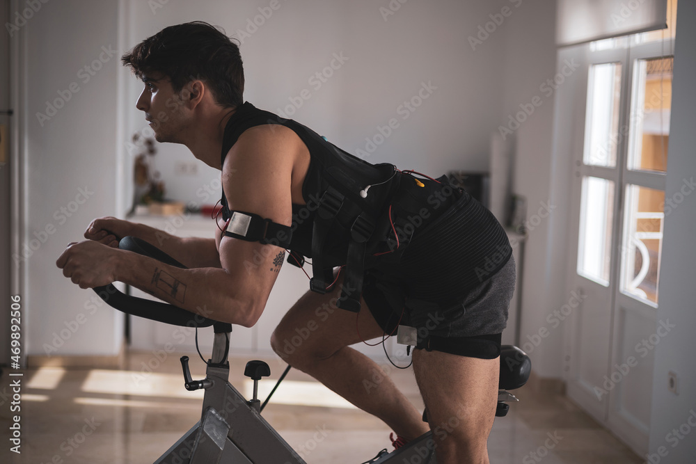 Obraz premium a young athlete riding a bike with an electrostimulation vest in a beauty clinic.