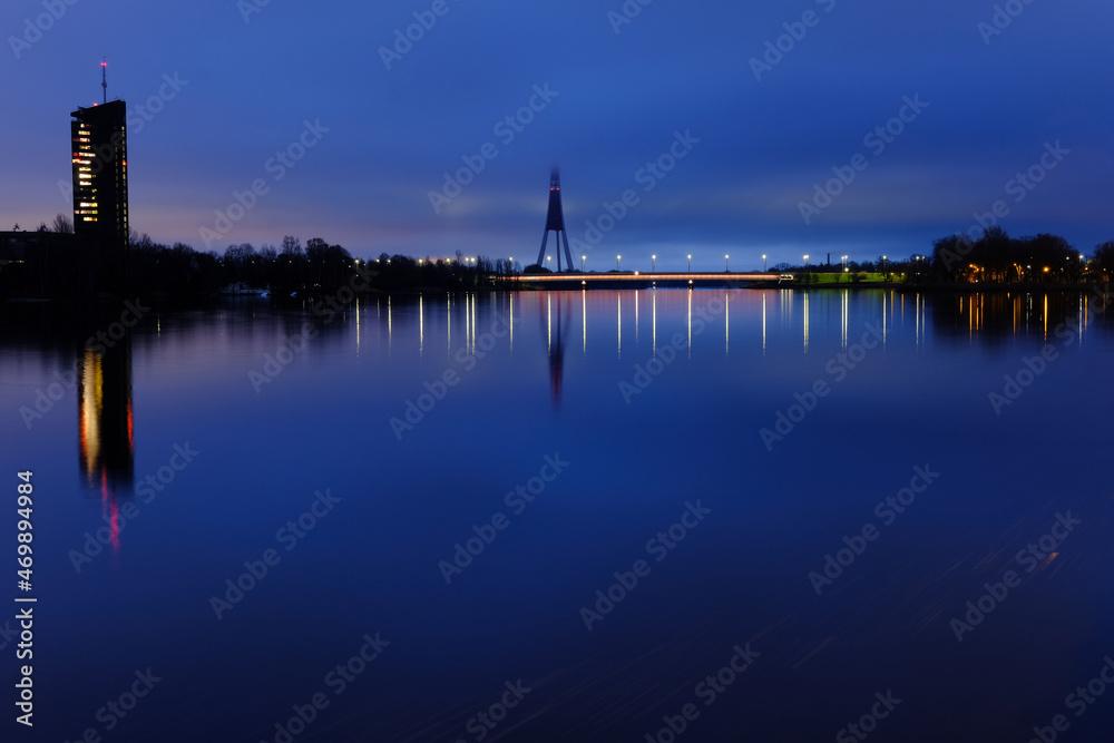 Reflection of night lights at dawn on the Daugava in Riga against the background of the televised tower