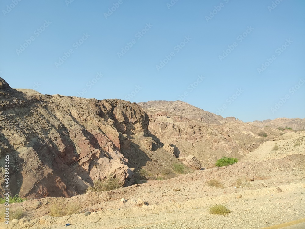 Région de hautes montagnes rocheuses, zone désertique et de la roche blanche ou rouge, circulation sur les flancs de la montagne, avec falaise, forte chaleur et ciel bleu, en Jordanie. 