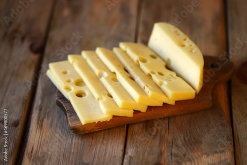 Sliced maasdam cheese on a wooden surface.