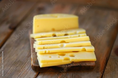 Sliced maasdam cheese on a wooden surface.