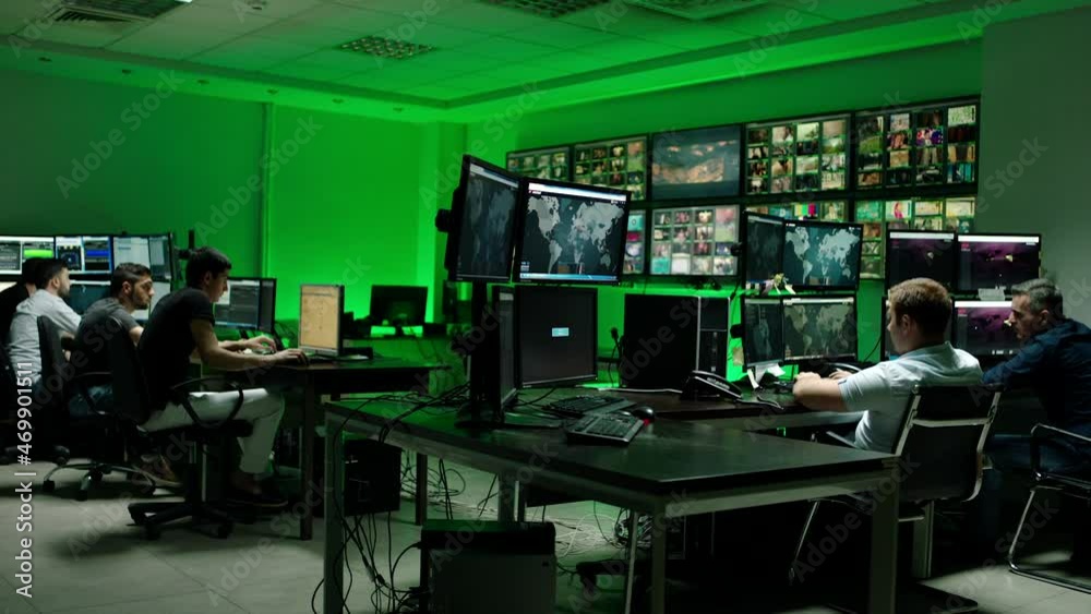 Male workers sitting near computers on monitoring room and working . Programmers or engineers using many laptops , computers , searching , following information and statistics . Cyber security office Male workers sitting near computers on monitoring room and working . Programmers or engineers using many laptops , computers , searching , following information and statistics . Cyber security office