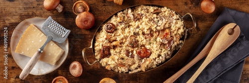 Risotto ai funghi panorama, mushroom risotto, rustic rice with mushrooms and cheese, panoramic banner on a dark wooden background
