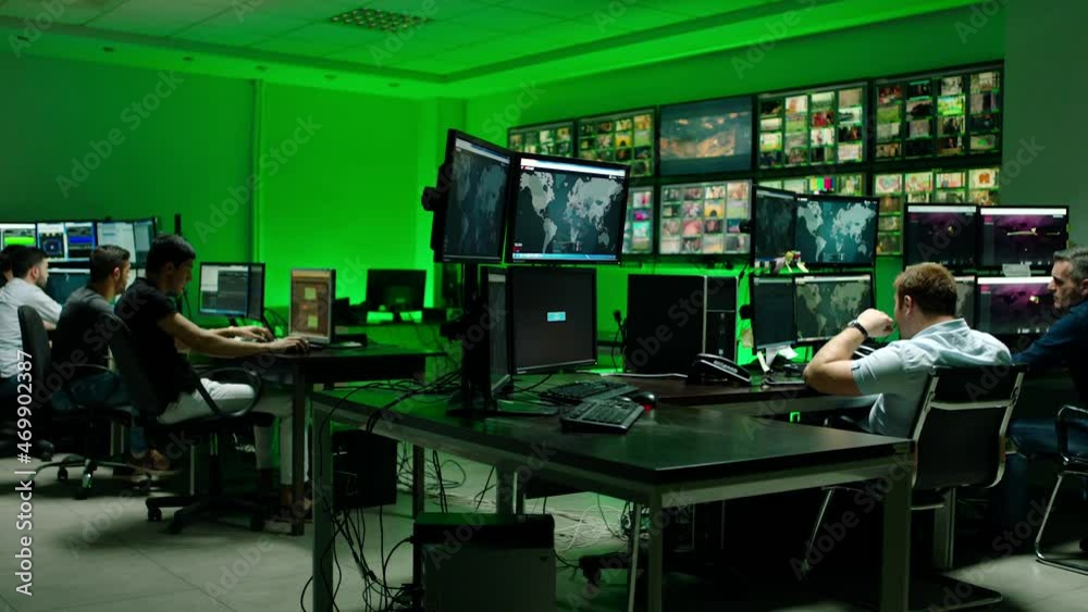Male workers sitting near computers on monitoring room and working . Programmers or engineers using many laptops , computers , searching , following information and statistics . Cyber security office Male workers sitting near computers on monitoring room and working . Programmers or engineers using many laptops , computers , searching , following information and statistics . Cyber security office