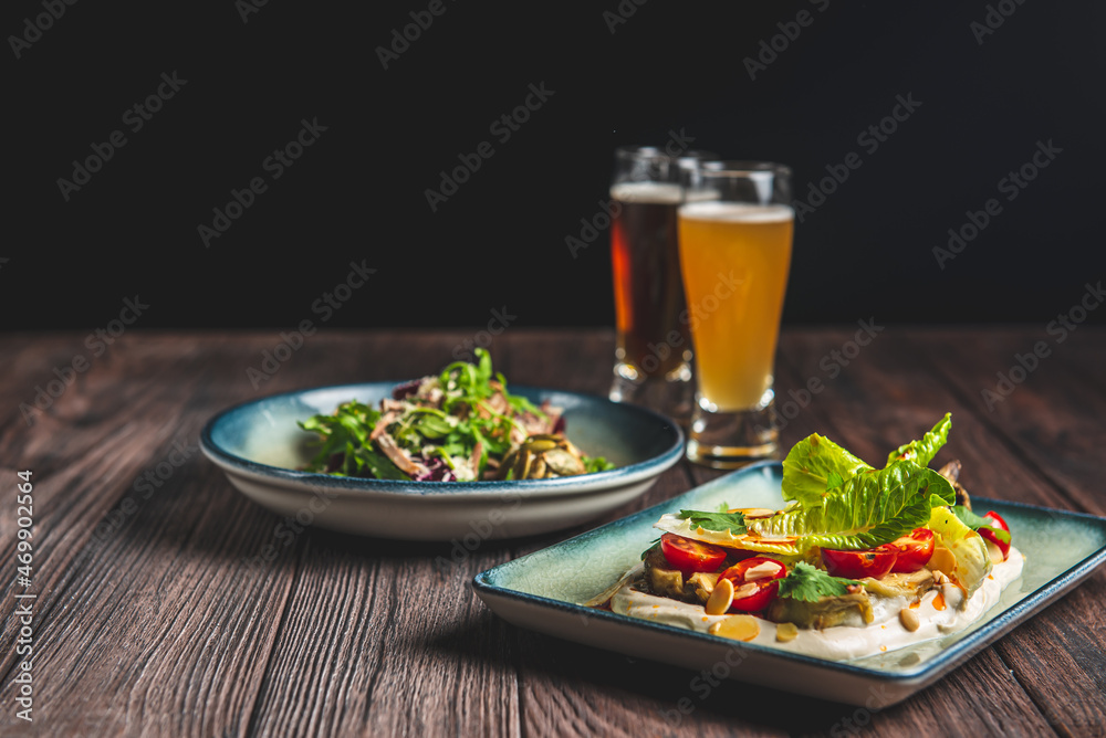 Two glass of beer and autumn or fall food over black background on rustic wooden table. Two glass of beer and autumn or fall food over black background on rustic wooden table.