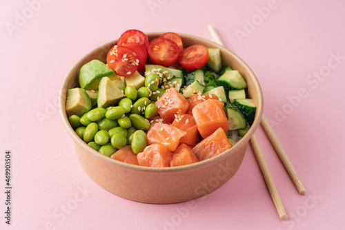 Salmon, avocado, cucumber, tomato, edamame beans and rice poke bowl on pink background photo