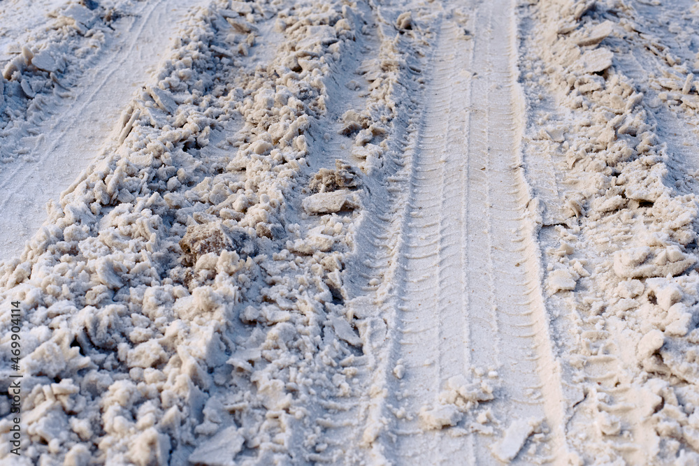 Road covered with snow, winter driving, dangerous road conditions. Tire tracks on snowy road, ice under the snow. Traction on winter road. Selective focus Road covered with snow, winter driving, dangerous road conditions. Tire tracks on snowy road, ice under the snow. Traction on winter road. Selective focus