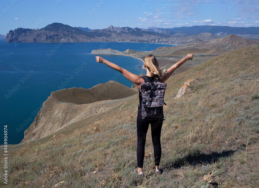 young woman hiker stands on the mountain against the background of the sea young woman hiker stands on the mountain against the background of the sea