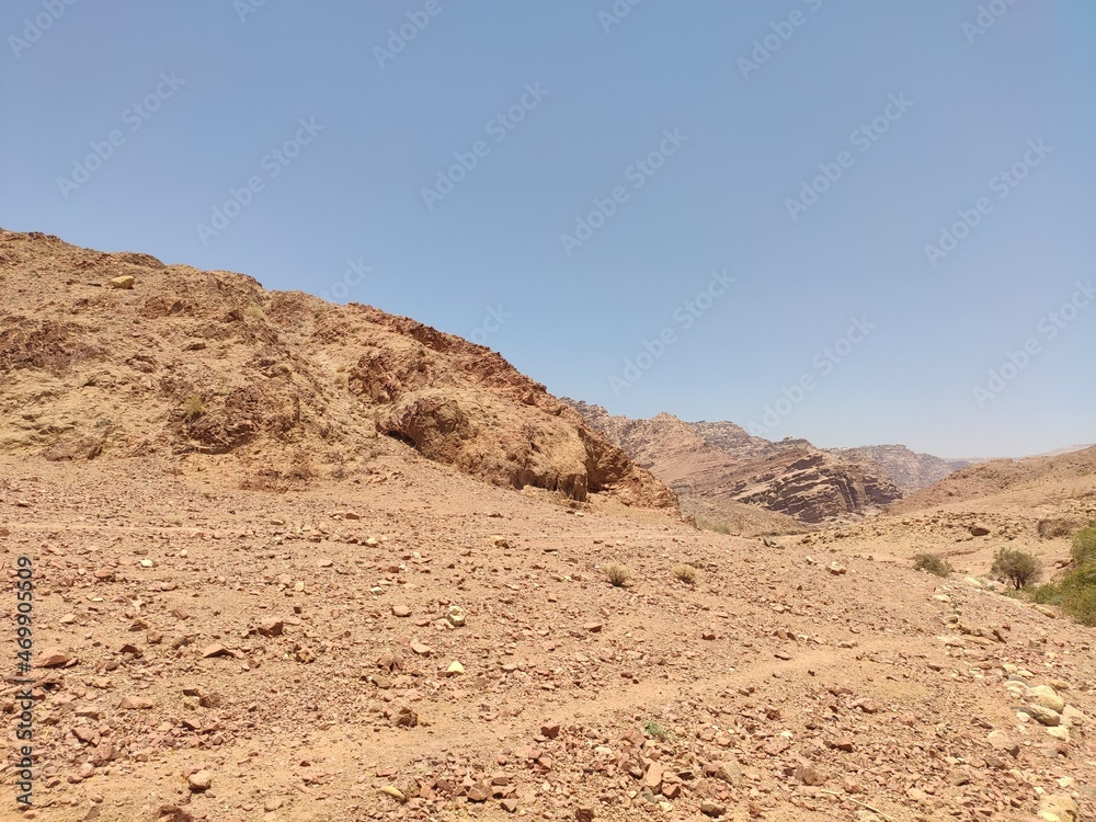 Dana, la plus grande réserve naturelle de Jordanie, marche en plein milieu d'une zone montagneuse rouge et blanche, avec un peu de verdure et de la forte chaleur, sans ombre, parcourir desert cailloux