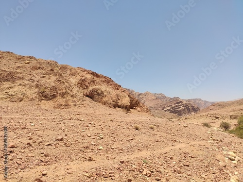 Dana, la plus grande réserve naturelle de Jordanie, marche en plein milieu d'une zone montagneuse rouge et blanche, avec un peu de verdure et de la forte chaleur, sans ombre, parcourir desert cailloux