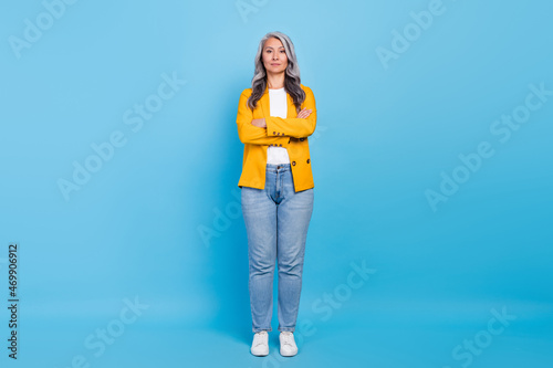 Photo of pretty shiny senior lady dressed yellow blazer arms folded smiling isolated blue color background