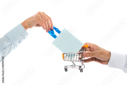 cropped view of man holding tiny shopping cart near woman with paper bag isolated on white photo