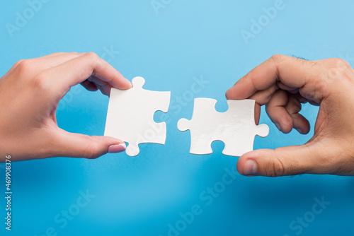 cropped view of female and male hands with jigsaw on blue