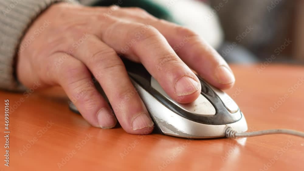 close-up of the hand of a pensioner holding a computer mouse. Training a psionary to work on a computer. An active elderly man spends his leisure time using a computer. Selective focus close-up of the hand of a pensioner holding a computer mouse. Training a psionary to work on a computer. An active elderly man spends his leisure time using a computer. Selective focus