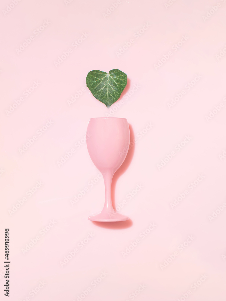 Pink glass and ivy heart shaped green leaf against pastel, milky background.  Minimal creative layout, skin care, hydration, natural beauty, love.