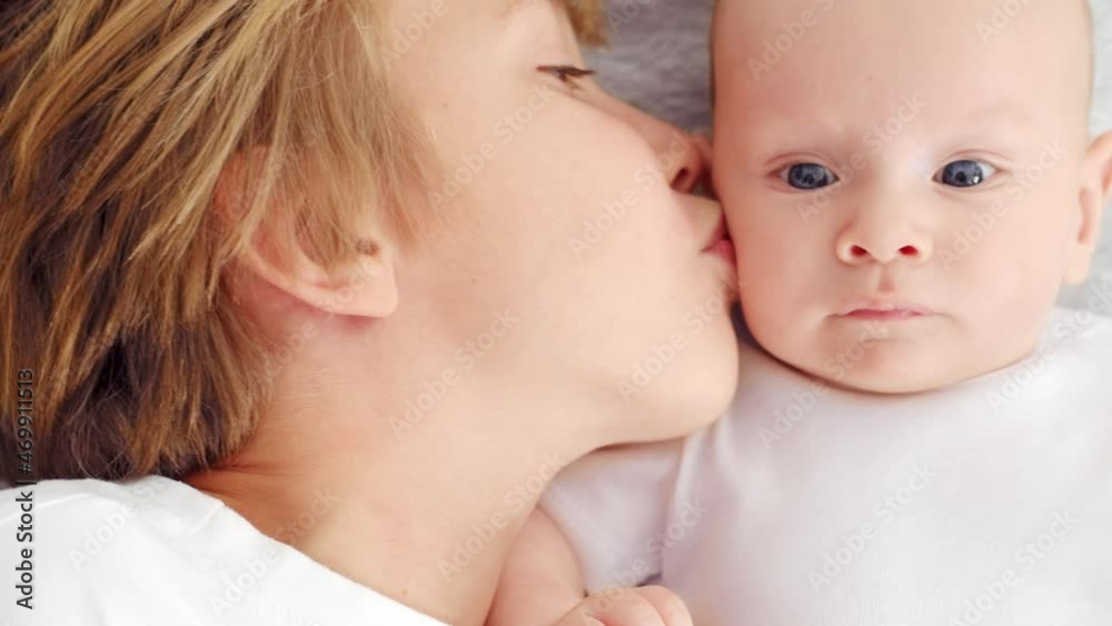 Older brother kisses his newborn brother on the cheek., top view. Happy family. Happy newborn baby with his brother. Healthy newborn baby in a white t-shirt with brother. Slow motion. Older brother kisses his newborn brother on the cheek., top view. Happy family. Happy newborn baby with his brother. Healthy newborn baby in a white t-shirt with brother. Slow motion.