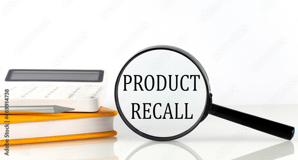 Magnifier with text PRODUCT RECALL with notebook, calculator on the white background Magnifier with text PRODUCT RECALL with notebook, calculator on the white background