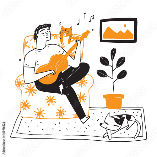 Happy young man playing guitar singing on sofa relaxing with pets, cats and dogs.