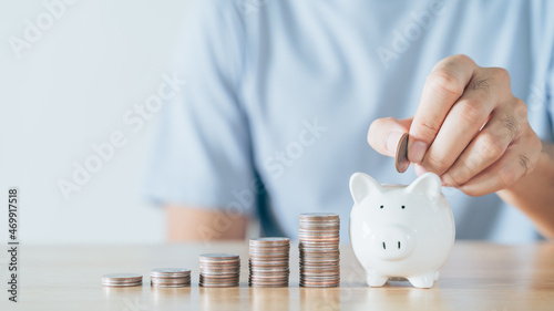 Closeup of man hand putting money coin into piggy bank for saving money. saving money and financial concept