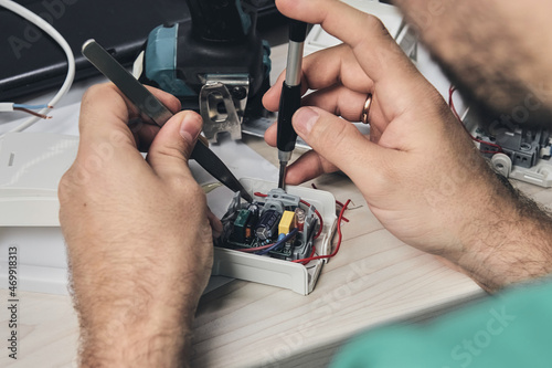 Repair of electronic devices, tin soldering parts. Hands of man holding screwdriver. Computer circuit board