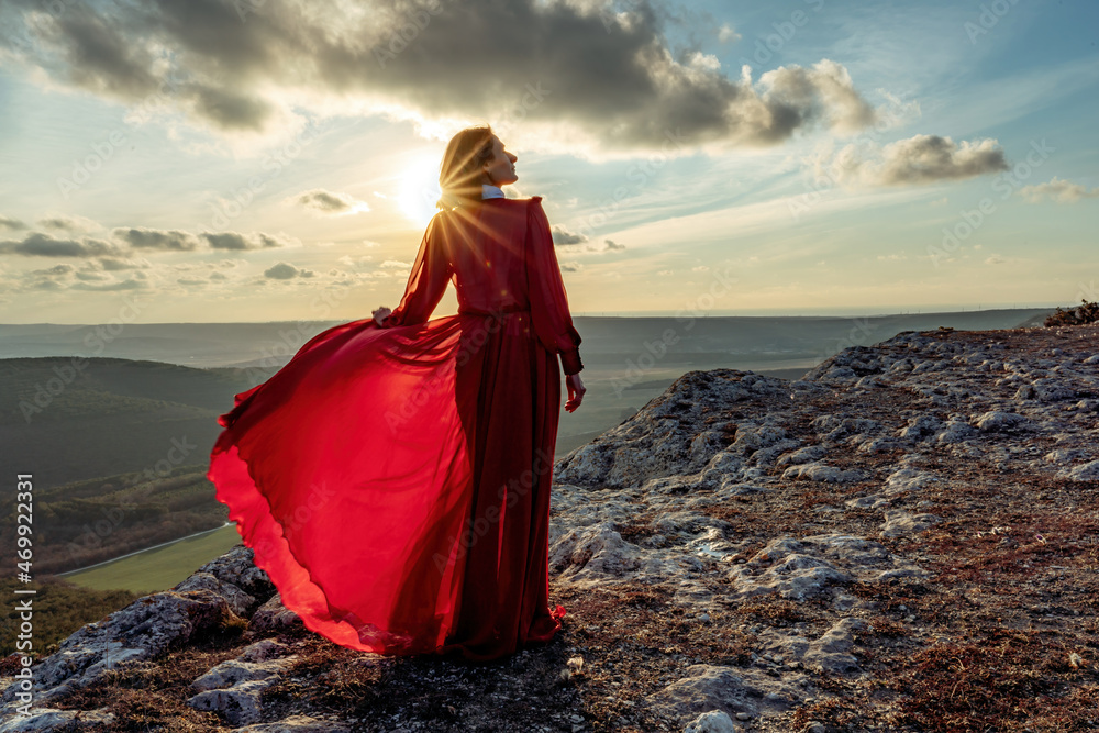 Rise of the mystic. sunset over the clouds with a girl in a long red dress. Stands on the mountain with a magical view. Rise of the mystic. sunset over the clouds with a girl in a long red dress. Stands on the mountain with a magical view.