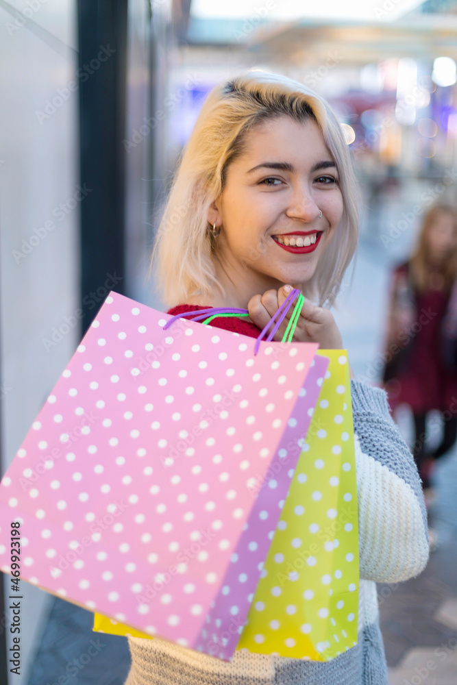 beautiful young blonde woman smiling with shopping bags outside