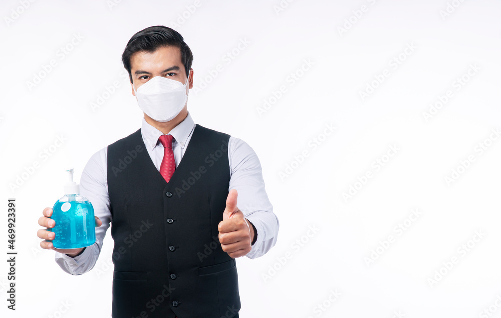 New normal social distancing safety health care concept. Confident positive handsome businessman holding alcohol gel bottles in own hand while showing thumb up standing over isolated white background. New normal social distancing safety health care concept. Confident positive handsome businessman holding alcohol gel bottles in own hand while showing thumb up standing over isolated white background.