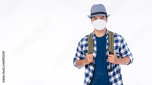 New normal lifestyle travel vacation concept. Traveler adventure handsome young man wear casual shirt, hat and protective mask safety with backpack standing over isolated white background.