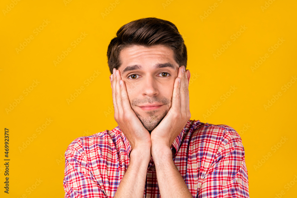Photo of happy positive young man hold hands face cheeks smile good mood isolated on yellow color background Photo of happy positive young man hold hands face cheeks smile good mood isolated on yellow color background