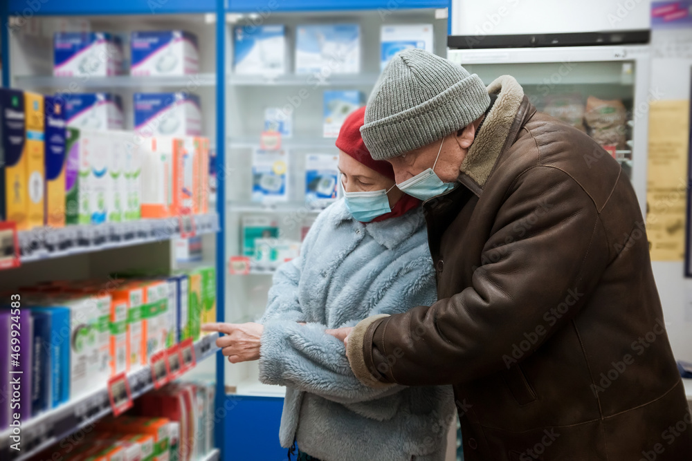 Elderly woman and man in protective medical masks in pharmacy
