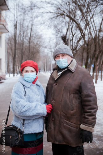 Elderly woman and man in protective medical masks on street.