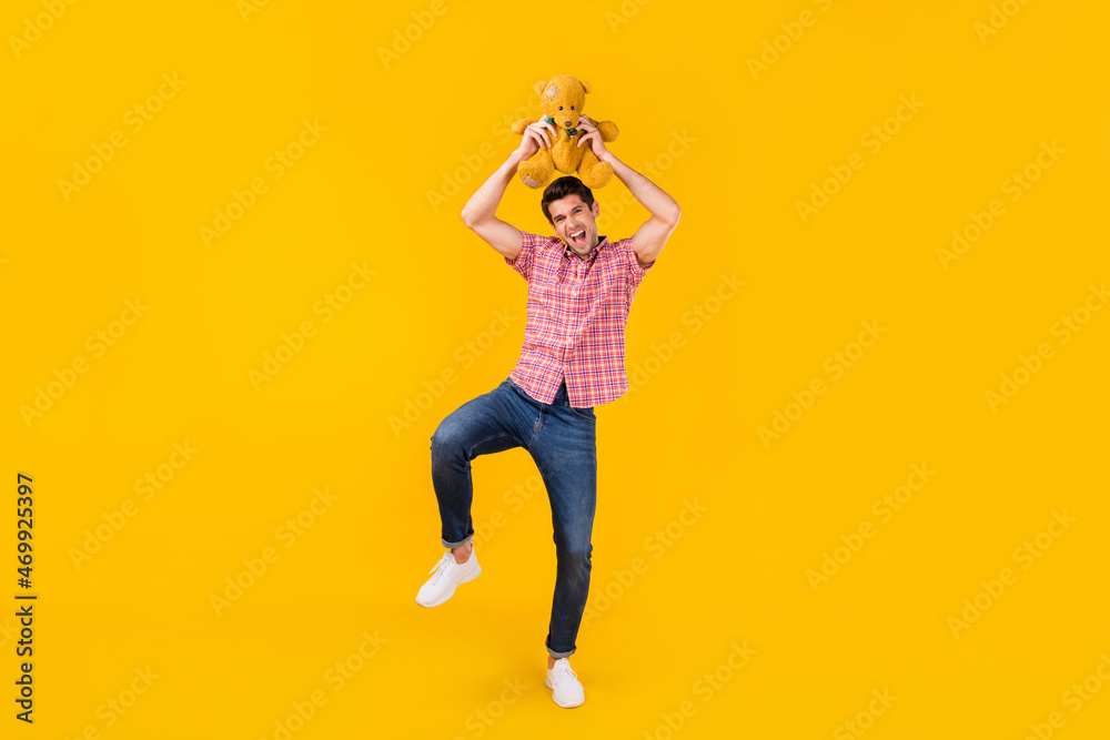 Full length body size view of nice carefree cheerful funky guy dancing with toy fooling isolated over bright yellow color background Full length body size view of nice carefree cheerful funky guy dancing with toy fooling isolated over bright yellow color background