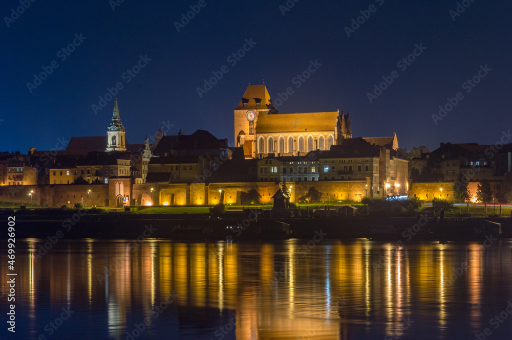 Old town of Torun with Church of St. John the Baptist and St. John the Evangelist. View on vistula river at night.
