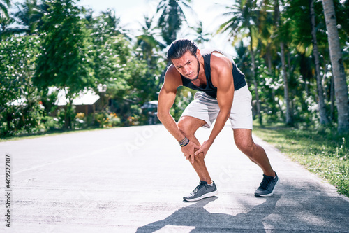 Running sportsman feeling pain after having his knee injured