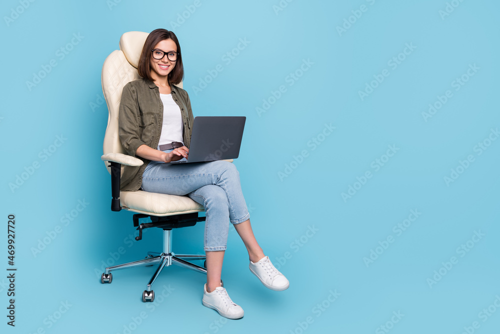 Full body photo of ceo lady sit chair use device texting typing message wear khaki denim outfit isolated over blue color background Full body photo of ceo lady sit chair use device texting typing message wear khaki denim outfit isolated over blue color background