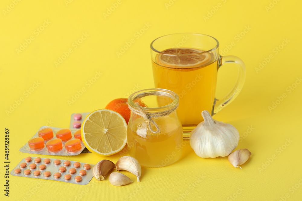 Concept of treatment colds with honey and garlic on yellow background