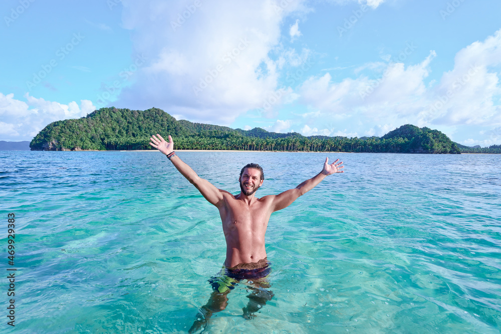 Vacation and freedom. Happy young man rising hands up bathing on tropical beach enjoying beautiful view. Vacation and freedom. Happy young man rising hands up bathing on tropical beach enjoying beautiful view.
