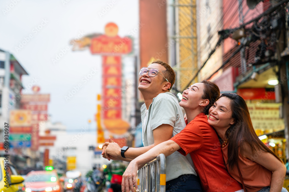 Group of Asian people tourist walking down street and shopping together at Chinatown in Bangkok city, Thailand. Male and female friends enjoy outdoor lifestyle travel and eating street food at night